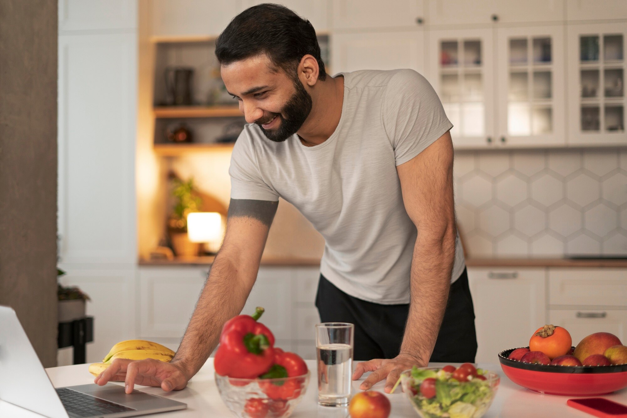 Pria menyiapkan makanan sehat di dapur rumah dengan sayuran segar dan bahan makanan di atas meja